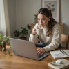 Donna seduta al computer che sorseggia un te